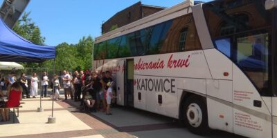 Na zdjęciu widać ambulans do pobierania krwi, przy którym stoi kolejka oczekujących na oddanie krwi. Ambulans stoi przed wejściem do Parku Tradycji, w którym mieści się oddział Siemianowickiego Centrum Kultury.